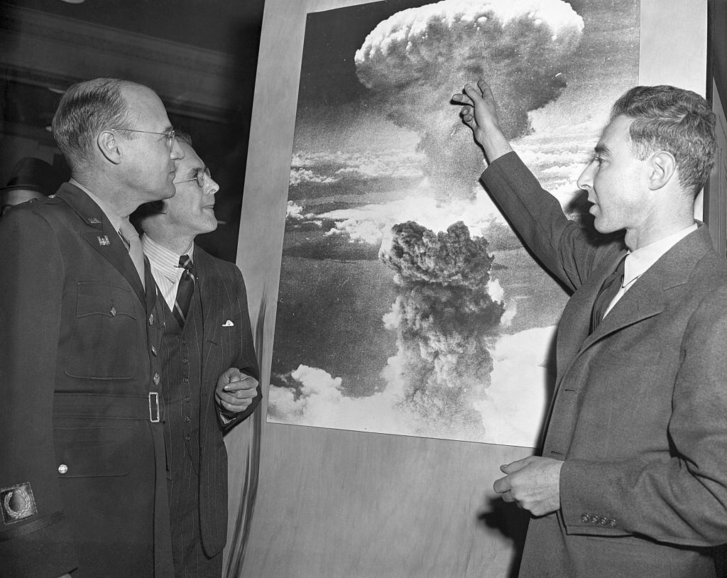 Three of the men who played leading roles in the development of the atomic bomb visit the American Chemical Society Atomic Exhibit in Grand Central Palace. Looking at a photo of the atomic explosion over Nagasaki, Japan, are left to right, Brig. Gen. K. D. Nichols, Prof. H.D. Smythe, and J.R. Oppenheimer, director of the Los Alamos, N.M. atomic labratory. | Getty.