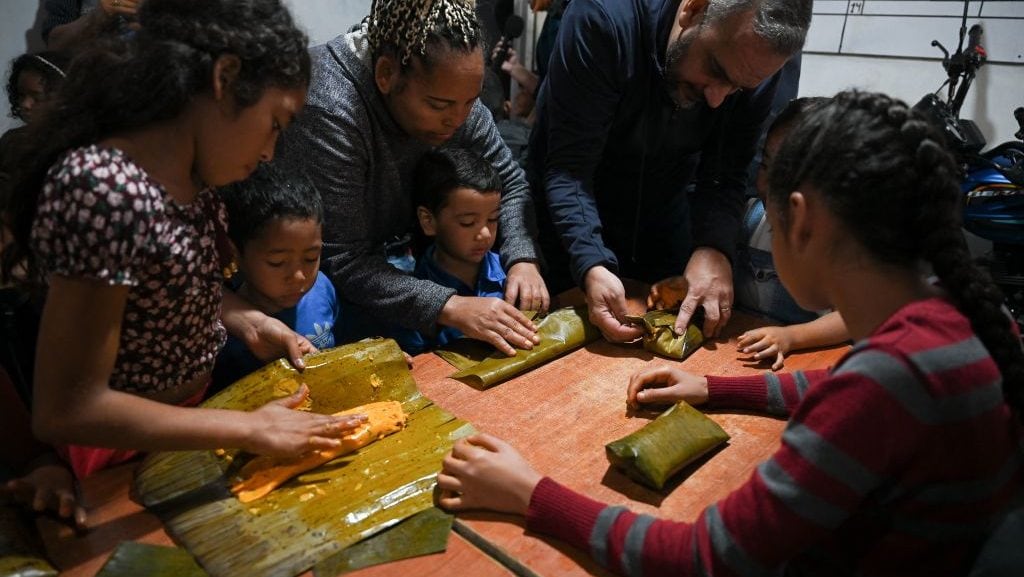 Niños aprenden a preparar hallacas, un plato típico navideño venezolano, durante una actividad organizada por la fundación ‘Cuento Contigo Siempre’ en el barrio Ojo de Agua de Caracas, el 27 de diciembre de 2022. (Federico Parra/Getty Images)