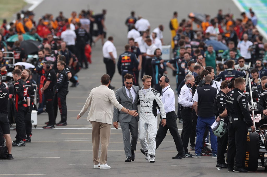 Brad Pitt, star of the upcoming Formula One based movie, Apex, and Javier Bardem talk on the grid during the F1 Grand Prix of Great Britain at Silverstone Circuit. Ryan Pierse/Getty Images.