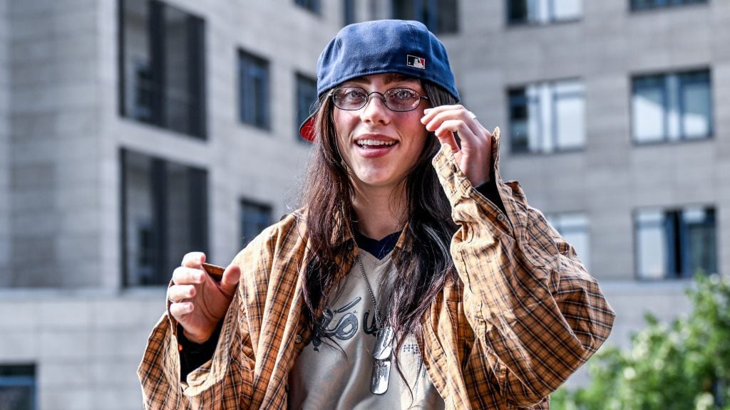 Billie Eilish is sitting on a ledge of a staircase railing known as the ‘Billie Eilish wall’. (Britta Pedersen/Getty Images)