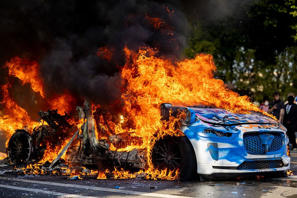 Flames engulf an autonomous Waymo vehicle during an anti-ICE protest in downtown Los Angeles, California, on June 8, 2025. The protest erupted after a wave of federal immigration raids began on June 7, with National Guard troops deployed to the city despite objections from local officials. Demonstrators called for an end to deportations and the dismantling of ICE. Benjamin Hanson / Middle East Images via AFP