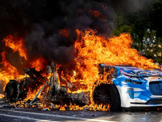 Flames engulf an autonomous Waymo vehicle during an anti-ICE protest in downtown Los Angeles, California, on June 8, 2025. The protest erupted after a wave of federal immigration raids began on June 7, with National Guard troops deployed to the city despite objections from local officials. Demonstrators called for an end to deportations and the dismantling of ICE. Benjamin Hanson / Middle East Images via AFP