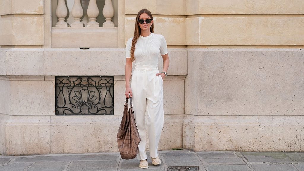 Diane Batoukina wears long, straight light brown hair with a side part, styled with a natural complexion and soft pink lipstick. Black rectangular sunglasses by Loro Piana are worn with a fitted white ribbed knit T-shirt by Artknit Studios. (Edward Berthelot/Getty Images)