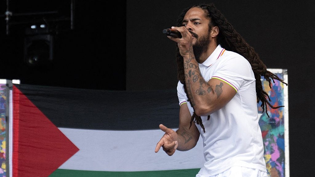 To the backdrop of a Palestinian flag, Bobby Vylan of British duo Bob Vylan performs on the West Holts Stage on the fourth day of the Glastonbury festival at Worthy Farm in the village of Pilton in Somerset, south-west England, on June 28, 2025. Oli SCARFF / AFP via Getty Images