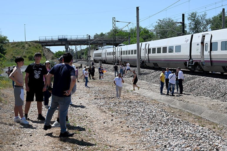 Passengers stand next to a stopped RENFE high-speed AVE train near Cordoba on April 28, 2025
