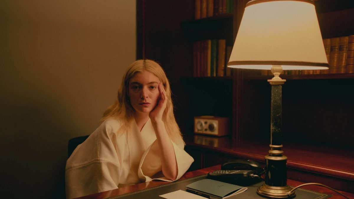 Lorde sitting at a desk, posing