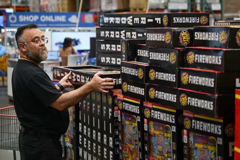 Varios compradores pasan junto a cajas de fuegos artificiales expuestas en una tienda Costco