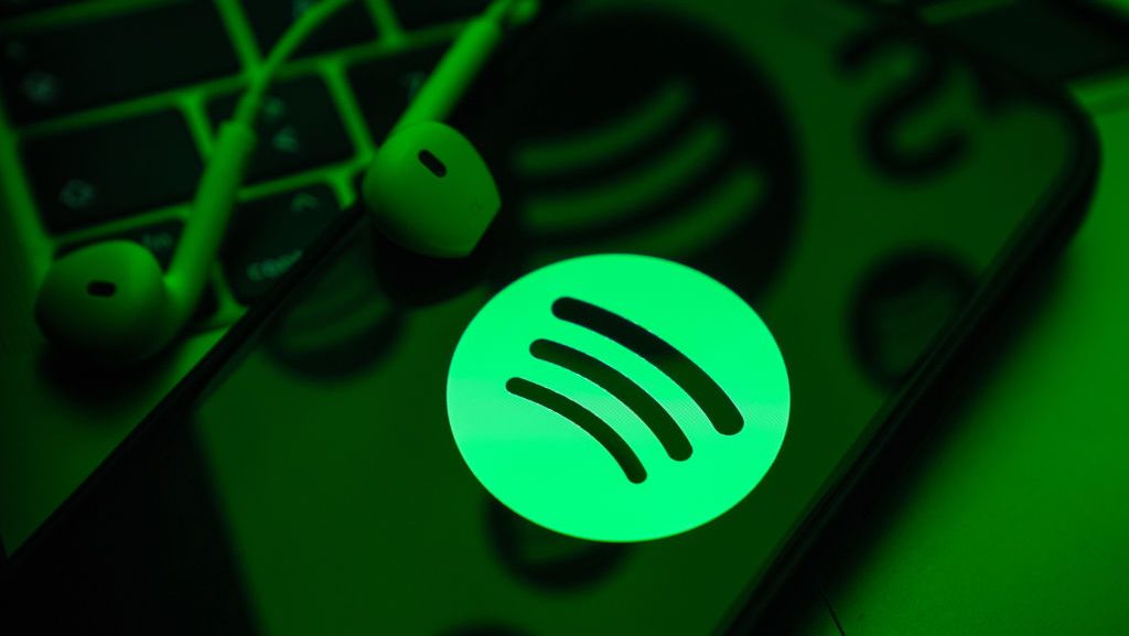 El logo de Spotify se ve en una pantalla de celular con auriculares alámbricos