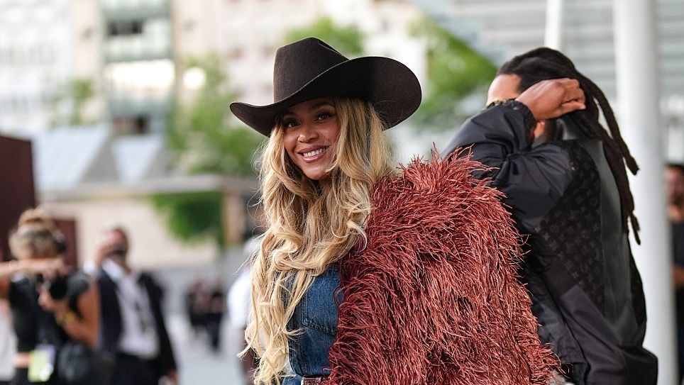 Beyoncé Knowles / Beyonce wears a cowboy hat, a burgundy faux fur fluff coat on one shoulder, a blue denim shirt, during the Louis Vuitton Menswear Spring/Summer 2026 show as part of Paris Fashion Week on June 24, 2025 in Paris, France. (Photo by Edward Berthelot/Getty Images)